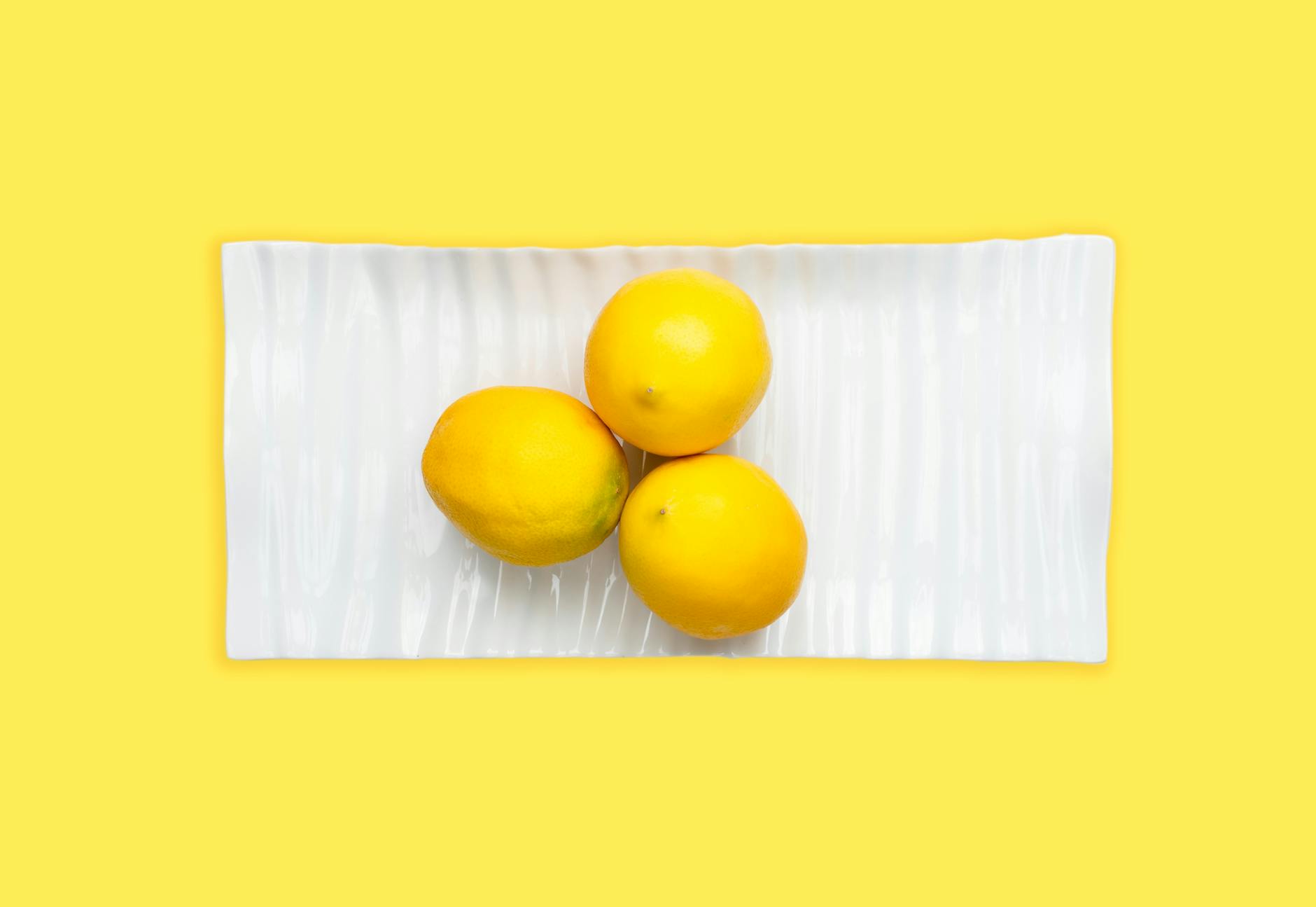 Hand holding a fresh lemon against a bright yellow background, symbolizing renewal and fresh starts