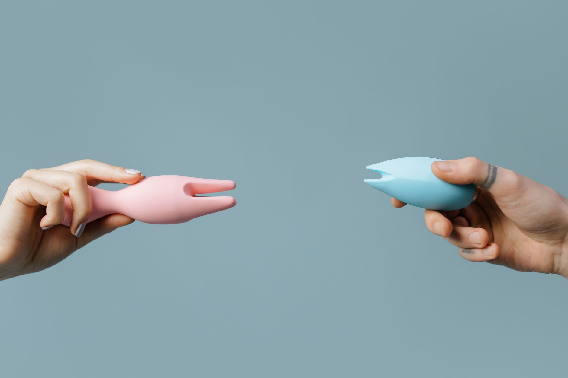 Hand holding an orange vibrator against a minimalistic purple backdrop, showcasing reconnection and sensuality.