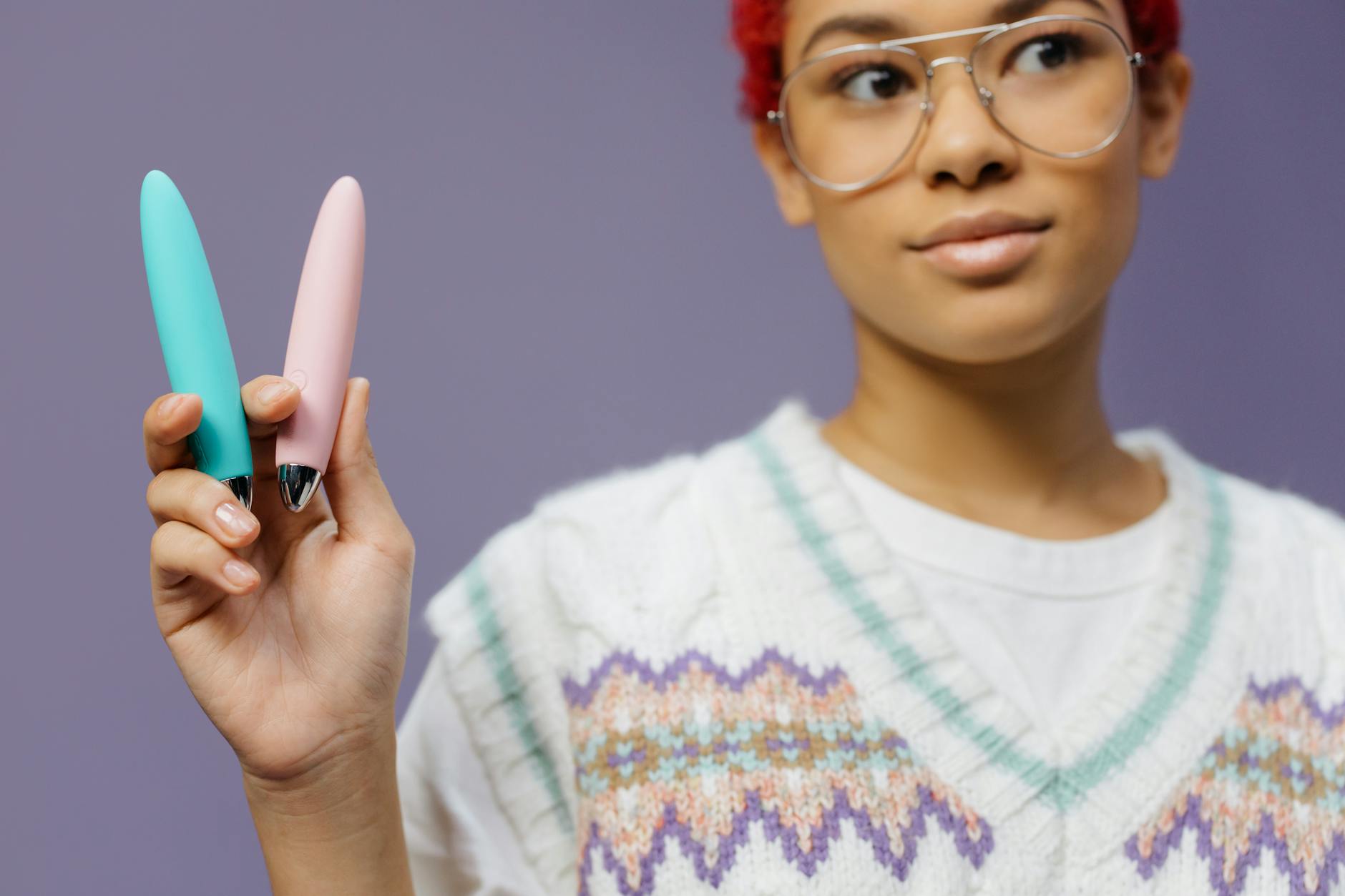 Woman holding vibrators against purple background, emphasizing pleasure and intimacy