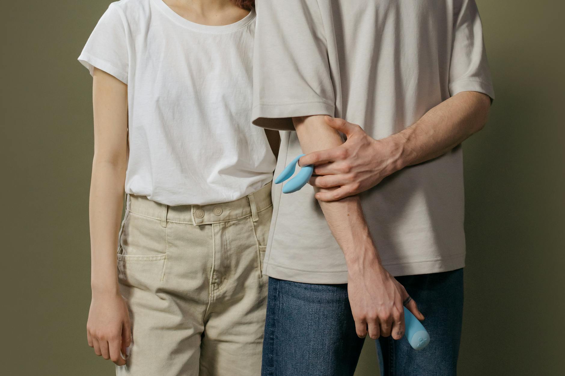 A couple standing together holding a blue vibrator, representing modern intimate connection during hormonal transitions.
